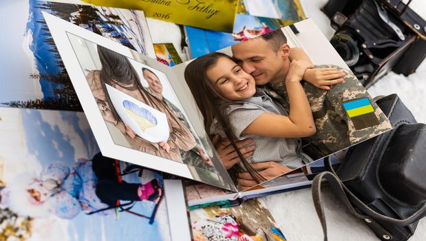 Family photos archive saved in brightly designed photo book; bright summer memories placed in the photobook. family with flag of ukraine.