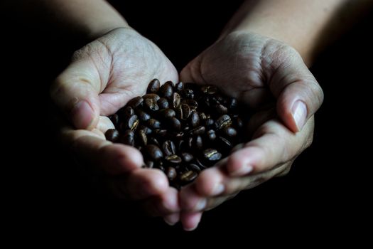 Coffee beans in the hands of heart shaped on wood table dark style and vintage