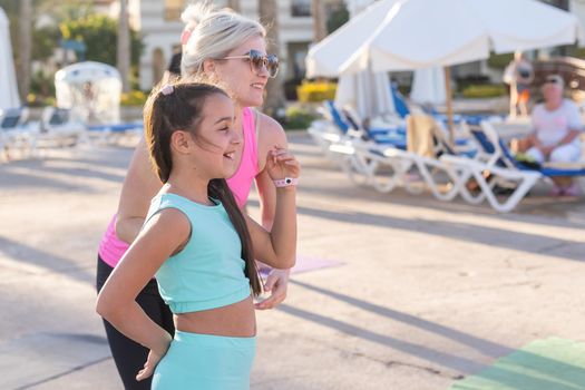 little girl doing sports exercises near hotel lounge chairs