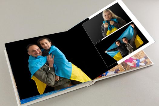 Family photos archive saved in brightly designed photo book; bright summer memories placed in the photobook. family with flag of ukraine.