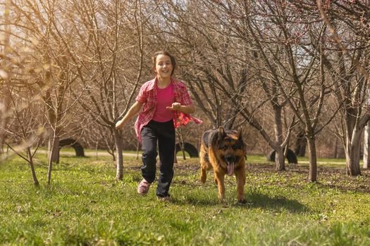 little girl running with his pet german shepherd.