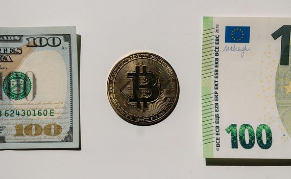 Digital cryptocurrency gold bitcoin lying between US Dollar and Euro banknotes. Difference between virtual money and cash. Concept of new virtual money. Top view. Close-up.