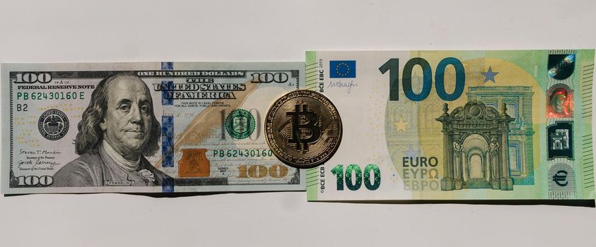 Digital cryptocurrency gold bitcoin lying between US Dollar and Euro banknotes. Difference between virtual money and cash. Concept of new virtual money. Top view.