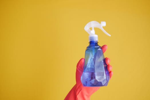 hand in blue rubber gloves holding spray bottle with copy space, top view