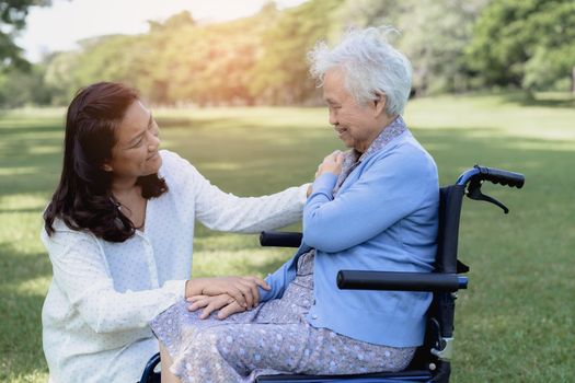 Caregiver help and care Asian senior or elderly old lady woman patient sitting on wheelchair in park, healthy strong medical concept.