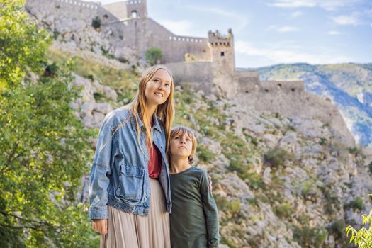 Mother and son travellers enjoys the view of Kotor. Montenegro. Bay of Kotor, Gulf of Kotor, Boka Kotorska and walled old city. Travel with kids to Montenegro concept. Fortifications of Kotor is on UNESCO World Heritage List since 1979.