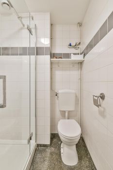 The interior of the bathroom made of white tiles with a glazed shower and a toilet