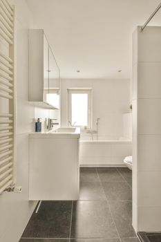 The interior of a bathroom decorated with white and black tiles in a modern house with a bathtub shower sink and toilet
