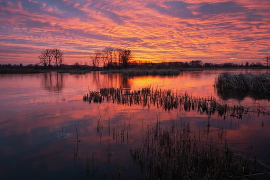 Colorful sky and clouds after sunset over a frozen lake, winter evening view, Stankow, Poland