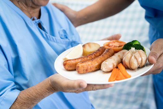 Asian senior or elderly old lady woman patient eating breakfast healthy food with hope and happy while sitting and hungry on bed in hospital.