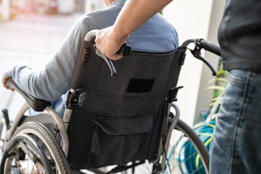 Caregiver help and care Asian senior or elderly old lady woman patient sitting on wheelchair at nursing hospital ward, healthy strong medical concept