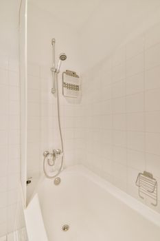 White bathtub with shower and ceramic tiles