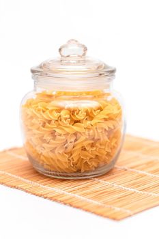 Uncooked Fusilli Pasta in Glass Jar on White Background. Raw and Dry Macaroni. Unhealthy and Fat Food. Italian Culture