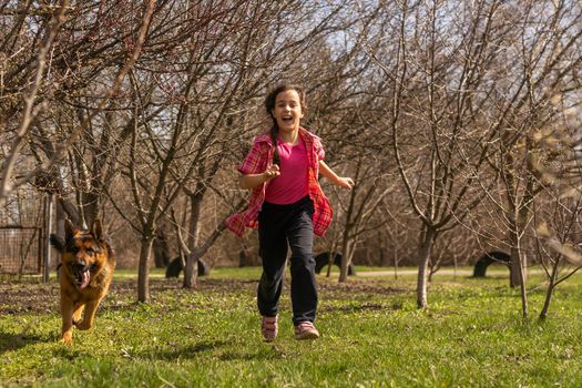 little girl running fast with a shepherd in the park.