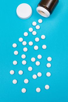 Global Pharmaceutical Industry and Medicinal Products - White Pills or Tablets Scattered from the Bottle, Lying on Blue Background, Top View, Flat Lay