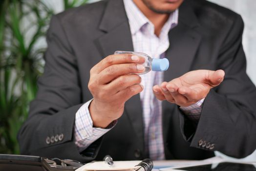 businessman using sanitizer gel on on office desk .