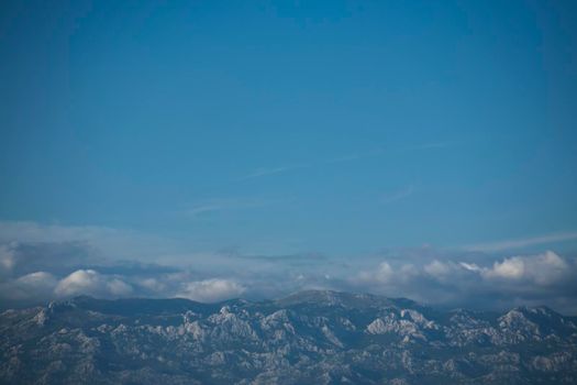 Blue skies and Velebit mountain peaks below. Copy space.