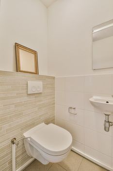 Bathroom interior finished with white tiles with a toilet and sink in a modern house