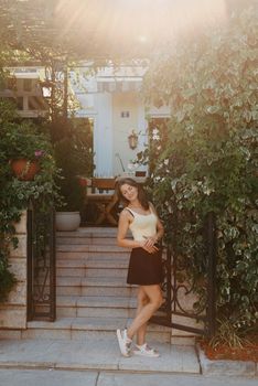 Girl tourist walking through ancient narrow street on a beautiful summer day in MEDITERRANEAN MEDIEVAL CITY , OLD TOWN bUDVA, MONTENEGRO. Young beautiful cheerful woman walking on old street at tropical town. Pretty girl looking at you and smiling