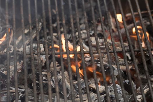 Empty flaming charcoal grill with open fire, ready for steak preparation barbecue concept with selective focus.