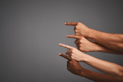 Studio shot of unidentifiable hands pointing upwards towards blank copyspace.