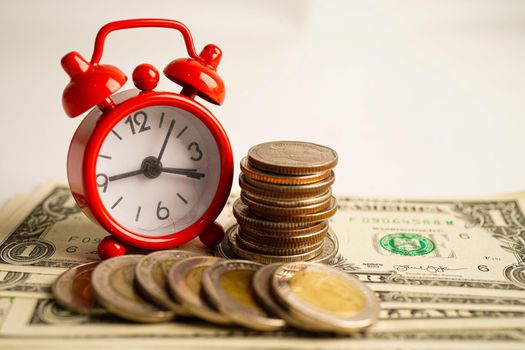 Alarm clock with coins on US dollar banknotes, finance installment loan time.