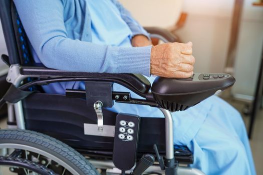 Asian elderly woman disability patient sitting on electric wheelchair in park, medical concept.