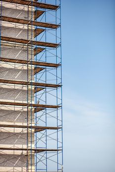 Scaffolding, metal mobile scaffold aginst blue sky background. Modern building is under construction, metal scaffolding.