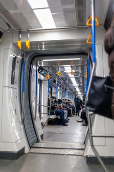 Public transport in the city. Moscow Metro. Yellow handrails for hands close-up. A full subway car lately in the evenings. There are a lot of people in a modern subway car.