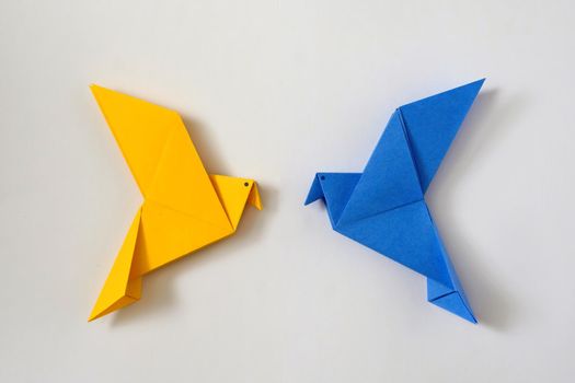 Two doves of peace as the color of the Ukrainian flag. Minimal concept of national political crisis of the world of help and support. Origami toy.