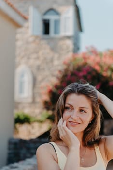 Girl tourist walking through ancient narrow street on a beautiful summer day in MEDITERRANEAN MEDIEVAL CITY , OLD TOWN bUDVA, MONTENEGRO. Young beautiful cheerful woman walking on old street at tropical town. Pretty girl looking at you and smiling