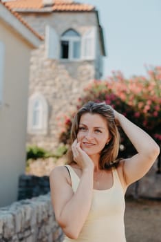 Girl tourist walking through ancient narrow street on a beautiful summer day in MEDITERRANEAN MEDIEVAL CITY , OLD TOWN bUDVA, MONTENEGRO. Young beautiful cheerful woman walking on old street at tropical town. Pretty girl looking at you and smiling