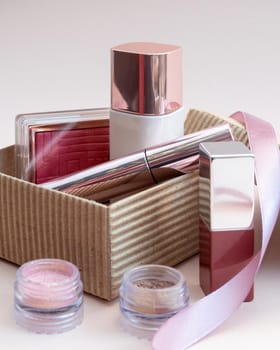 a set of cosmetics for a female face and eye makeup in a brown craft box on a pink background. photo