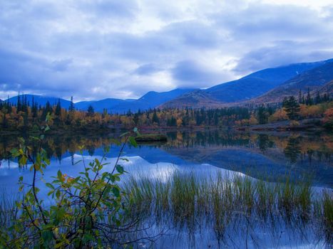 Reflection of mountains and clouds in the calm surface of the lake. Peaceful landscape. Khibiny. photo