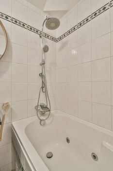 Bathroom interior with white tiles and a pattern on it, as well as with a bathtub and shower