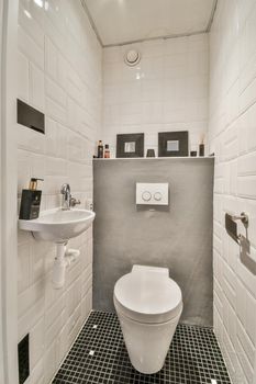 Bathroom interior with white tiles and a pattern on it, as well as with a ceramic sink and a toilet