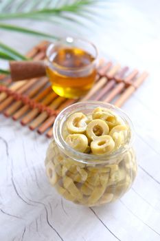 bottle of olive oil and fresh olive in a container on table