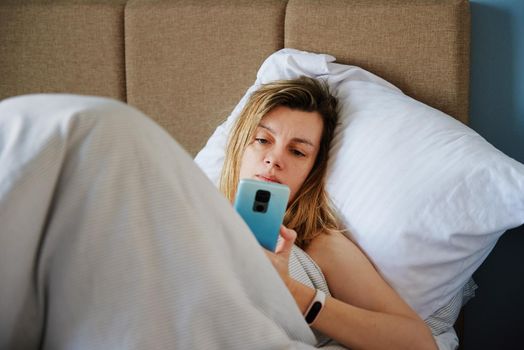 Caucasian woman relaxing in bed and use smartphone, Online communication and social media concept, Lazy weekend