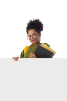 Friendly ethnic black female high school student in eyeglasses with banner and composition book isolated on white background