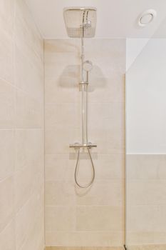 Bathroom interior finished with beige tiles with a shower cabin in a cozy house