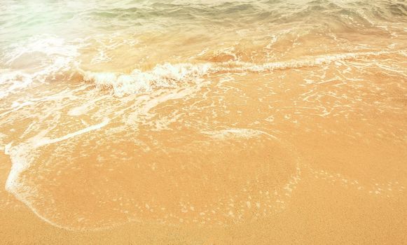 Magnificent summer sea abstract beach background with Golden sand, white foam, blue ocean and sunlight.