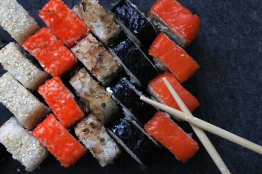 A set of rolls and sticks for sushi on a dark background. Japanese cuisine. View from above. Background.