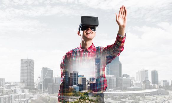 Young man with virtual reality headset or 3d glasses over cityscape background