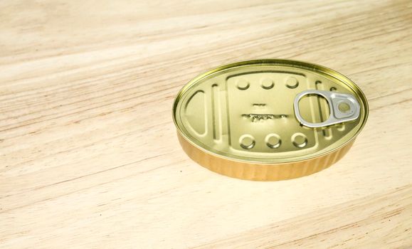 Golden can of preserved food on wooden table background