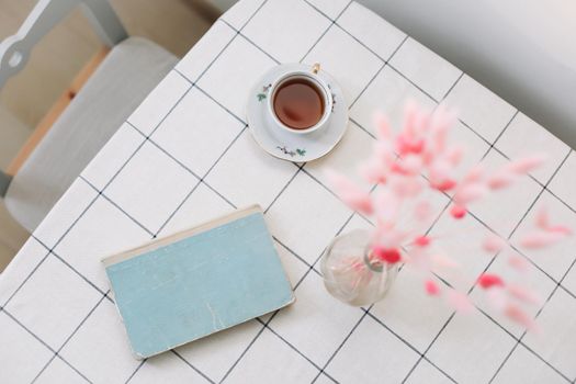 modern interior design in contemporary and cozy living room with dry plants in vase, book and tea cup on the table