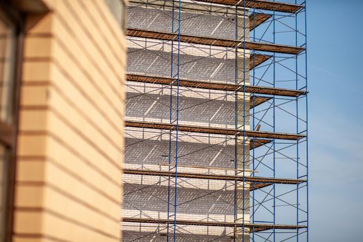 Scaffolding, metal mobile scaffold aginst blue sky background. Modern building is under construction, metal scaffolding.