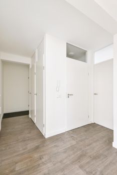 Exit from a small cozy empty room with a parquet floor and a white door