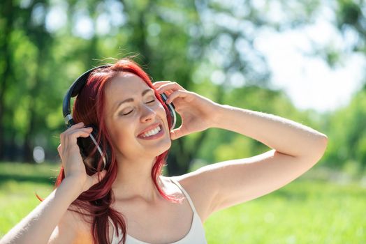 Young attractive woman listens to music in the park. Enjoying music in the park