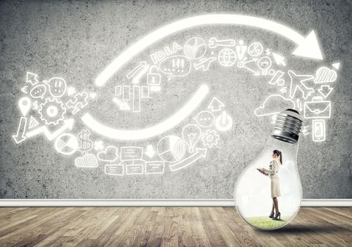 Businesswoman inside of light bulb in empty concrete room