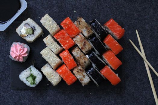A set of rolls and sushi sticks on a dark background. Japanese cuisine. Background. Healthy eating.